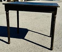 Front view of the antique solid oak table showing its original stained finish, turned legs, and the table top's condition including slight warp.