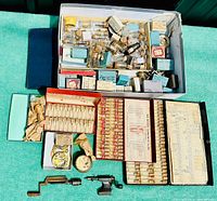 Overhead view of entire lot showing boxes of vials, trays of glass tubes, movements and hand tools on green surface