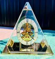 Front view of Seiko pyramid mantle clock with clear case and visible gold skeleton movement.