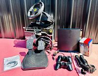 Full lot including PS3 console, controllers, steering wheel, pedals, game cases, and setup manual. Taken to show all components included.