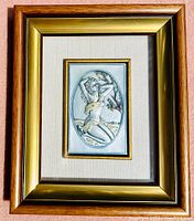Framed high relief sterling silver artwork by Bruno Castellani, depicting a kneeling partially clad female figure with fabric draped over body, under glass in a wood and gold-tone frame.