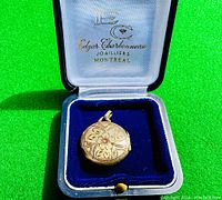 Locket front in original presentation box showing floral engraving