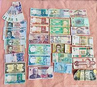 An overview image showing multiple vintage banknotes from various countries including Canada, Mauritius and others arranged on a cloth surface.