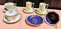 Overview of all vintage bone china cups and saucers on a pink surface showing various floral and gold pattern styles
