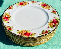 Stack of 9 vintage bone china plates with Old Country Roses floral pattern and gold scalloped edges, viewed from side angle