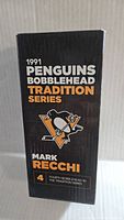 Black box with orange and white text stating '1991 Penguins Bobblehead Tradition Series' and featuring Mark Recchi name and team logo.