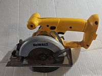 Side view of yellow and black cordless DeWalt DW936 circular saw showing blade, handle, and base plate with wear and dirt present.