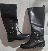 Side view of black leather boot showing decorative buckles and low heel.