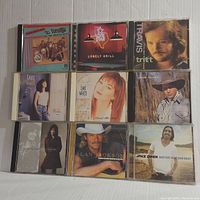 Photo showing nine country music CDs including albums by The Vandals, Lone Star, Travis Tritt, Lari White, Mark Collie, Alan Jackson, and Jake Owen.