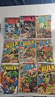 Photo shows nine vintage Incredible Hulk comics in three rows on a flat white surface. Covers are colorful with various depictions of the Hulk in action or facing enemies.