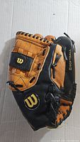 Side view of the black and tan leather Wilson softball glove with logo and 'Softball' branding.