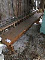 Long view of the wooden bench showing its entire length and surface condition with dust and dirt.