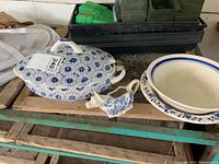 Lidded soup dish, cow-shaped gravy server, and two blue and white bowls on wooden table.