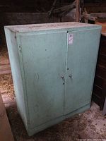 Closed view of large vintage painted wood storage cabinet from front left angle in storage environment.