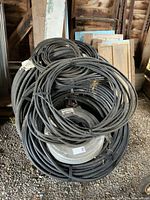 Overall view of multiple black cable coils stacked in barn