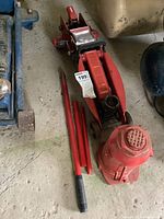 View of both hydraulic jacks on concrete floor, showing Motomaster car jack with handle and Tork bottle jack with lifting rods beside them.