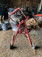 Cement mixer with red metal frame and wheels seen from side angle showing full structure.