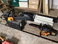 Two orange and black Poulan Pro chainsaws on wood bench; two plastic carrying cases behind
