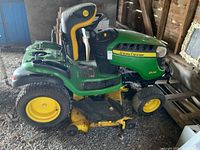 Side profile of John Deere D170 tractor showing green body, yellow wheels, black and yellow seat, and mower deck