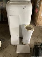 Front view of Toshiba portable AC unit with exhaust hose and window panels arranged in front