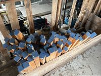 Wood pieces approximately 1.5x1.5 inches thick with blue painted ends and slanted cuts.