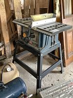 Full view of the Ryobi table saw on its metal stand with side extension wings.