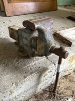 Side view showing the full length of the vintage cast iron bench vice, handle extended.