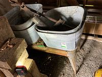 Two galvanized wash tubs on the rack with pump laid across