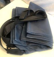 Folded navy laundry sacs with black straps visible, showing material and strap details.