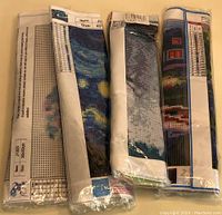 Rolled and wrapped diamond painting canvases showing partial printed designs and symbol charts for diamond placement.