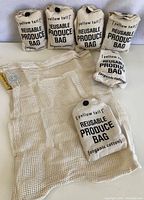 Six rolled up organic cotton produce bags with 'yellow tail' branding surrounding one opened mesh bag.