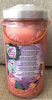 Back of the pink cylindrical container showing colorful Bright Fairy Friends branding, fairy character graphics, and multi-language text describing the product and magical fairy story.