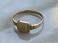 Front view of antique 10K gold signet ring showing letter M engraving on flat rectangular face, ring band slightly bent.