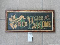 Full view of the antique framed motto sign with the phrase 'There is No Place Like Home' in multicolored decorative fonts and floral design on black background.