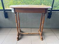 Front view of antique oval pine end table showing turned legs, stretcher base, and single drawer under tabletop.