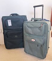 Two-piece luggage set showing black Atlantic suitcase and green McBrine suitcase with telescoping handles extended, standing upright on floor
