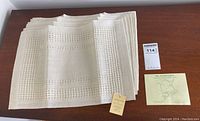 Top view of six stacked natural beige handwoven placemats with Loomcrafters tag visible.
