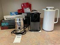 Front view of coffee machine, milk frother, thermos, and coffee pods showing overall lot contents and condition.
