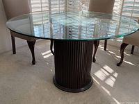 Full view of round glass top table showing clear glass surface and fluted base