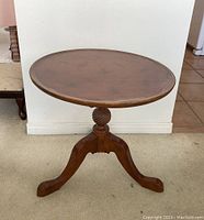 Front view of the round tilt-top pedestal end table showing carved spiral central column and tripod leg base.