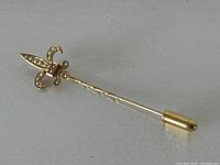Full view of the entire pin showing the gold shaft with a twisted pattern and the Fleur-de-lis head with pearls, including the gold cap at the end of the pin.