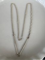 Full length view of the necklace laid out showing the chain and V-shaped sterling silver pendant.
