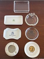 Seven vintage ashtrays and small dishes arranged on a wooden surface showcasing different designs and logos