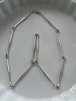 Entire necklace arranged on white dish to show shape and link design