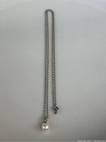 Full view of necklace laid flat showing chain and pearl pendant