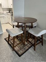 Full lot view showing round table and four stools on rug in room setting