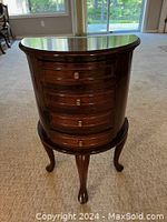 Front view of the four-drawer side cabinet showing semi-circular shape, dark wood finish, brass drawer knobs, and carved legs.