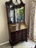 Full view of tall wooden cabinet with upper glass doors, drop-down leaf, and lower drawers.