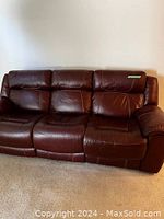 Front view of three-seat burgundy leather couch against wall