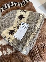 Knitted wool hat placed on top of the brown alpaca poncho, showing the knit pattern and texture.